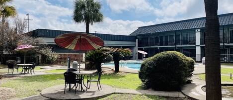 A courtyard with a pool, outdoor seating, and a building with balconies.