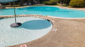 A swimming pool with a pebble border, a no diving sign, and a lounge chair with a canopy. - Extended Stay SA (San Antonio)