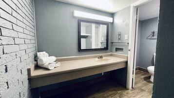 Un baño con un lavabo color beige, un espejo y un inodoro. Hay toallas en la encimera.