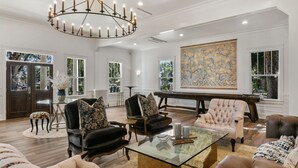 A spacious living room with a grand piano, elegant furniture, and a large painting on the wall.