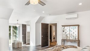 A spacious bedroom with a large bed, a wooden headboard, and a view of the outdoors.