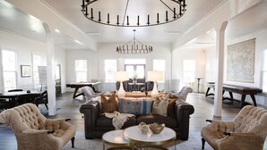 A spacious living room with a large sofa, two armchairs, a coffee table, and a chandelier.