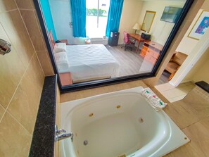 Une chambre d’hôtel avec un grand lit, une salle de bain avec baignoire, un bureau et une chaise.