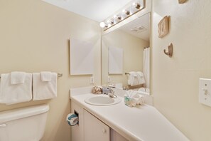 Un baño con lavamanos, espejo, toallero y retrete.