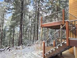 A wooden staircase with metal railings leading to a building surrounded by a snowy forest. - Secluded Cabin in the Beautiful Black Hills! Admire the Breathtaking Scenery!  (Lead)