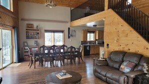 Un salón amplio con escalera de madera, un comedor con sillas de madera y una cocina con armarios de madera.
