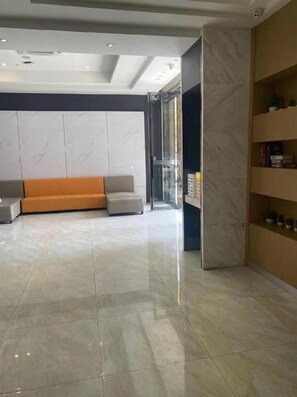 A modern lobby with a reception desk, seating area, and a glass elevator. - City Comfort Inn Wuhan Guanggu Textile University (Wuhan)
