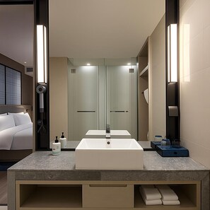 Een moderne hotelbadkamer met een grote spiegel, een dubbele wastafel en een douchehoek.