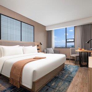 Een moderne hotelkamer met een groot bed, een bureau en uitzicht op de stadsbelangrijkste punten.