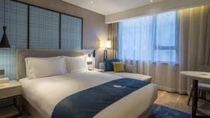 Een hotelkamer met een groot bed, een bureau, een stoel en een raam met gordijnen.
