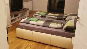 Une chambre avec un lit en mezzanine, un téléviseur posé sur un meuble et une vue sur un couloir.