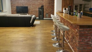Un salon moderne avec une cheminée, un téléviseur et un coin bar équipé de tabourets.