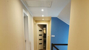 Un couloir doté d’un plancher en bois, de murs de couleur beige et d’un mur d’accent bleu.