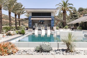 Et moderne hus med pool, omgivet af palmer og ørkenplanter.
