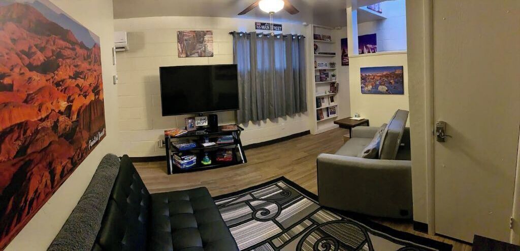 Un soggiorno con un divano, una televisione, una libreria e un quadro di grandi dimensioni.