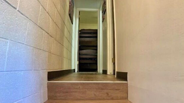 Un pasillo estrecho con escalones de madera que conducen a una escalera oscura.