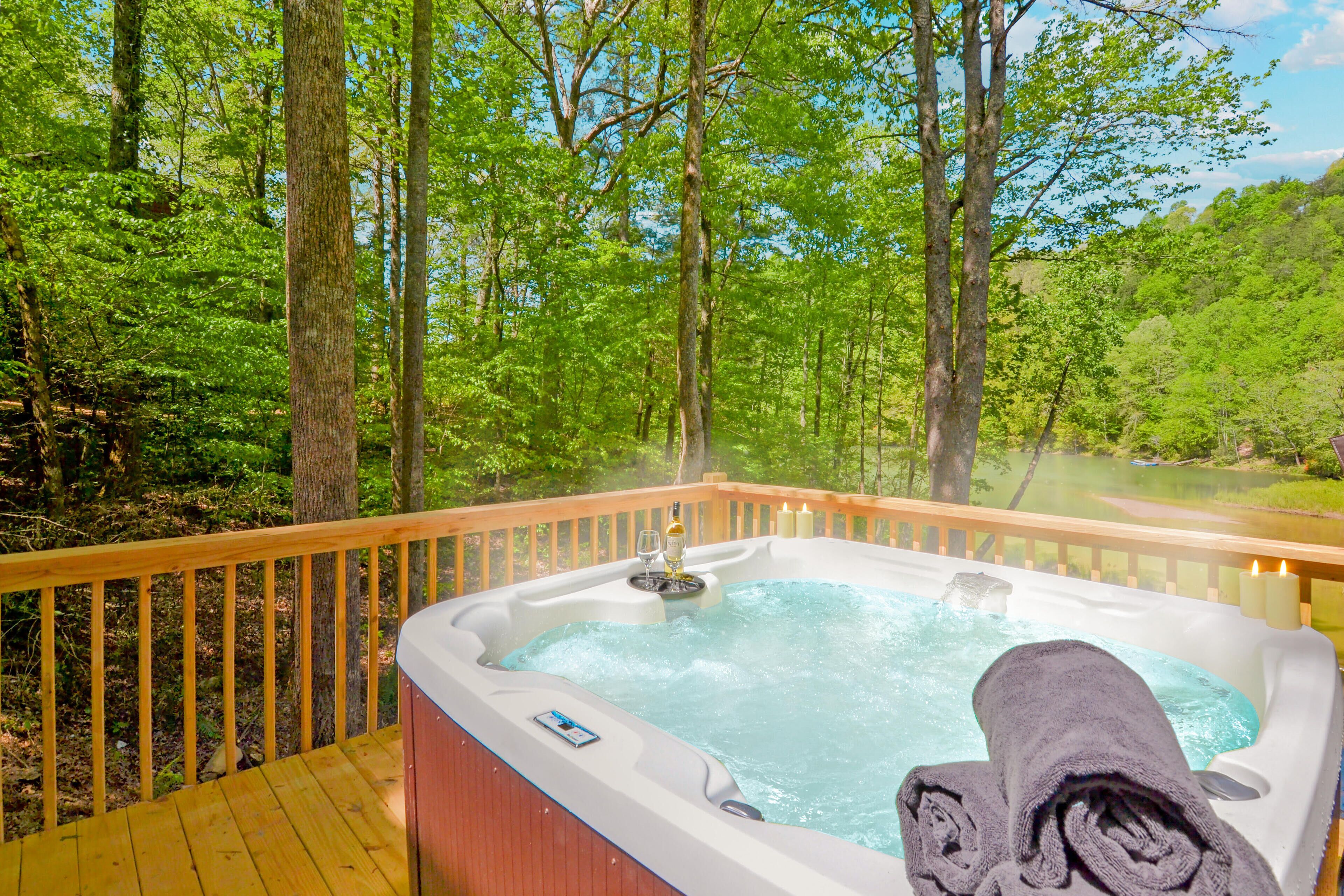 Un bain à remous sur une terrasse en bois, avec vue sur une forêt et un lac.