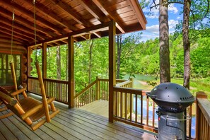 A wooden deck with a grill and a rocking chair.
