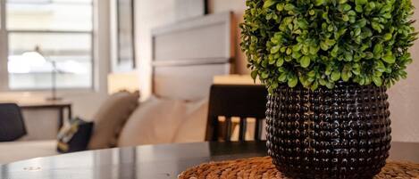 A potted plant on a woven placemat on a table in a room with a modern design, featuring a sofa and a lamp.