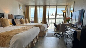 Habitación de hotel con dos camas, un escritorio, una silla, un televisor y vistas a la ciudad.