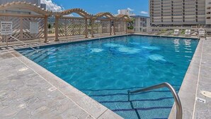 Una piscina con muelle de madera y puesto de socorrista.