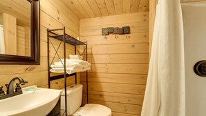 Ein Badezimmer in einer Holzhütte mit Waschbecken, Toilette und Ablagefläche mit gefalteten Handtüchern.