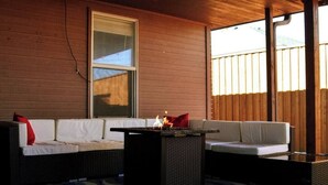 A covered patio area with two white sofas, a black table, and a blue and white striped rug. - McKinley House Prime - Patio, Pool and Garage (Amarillo)