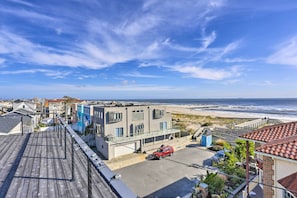 A coastal residential area with a view of the ocean, featuring modern houses, a wooden deck, and a parked car. - Luxury Long Beach Villa with Ocean Views! (Long Beach)