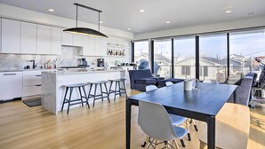 Una cocina moderna con armarios blancos, una isla grande y un comedor con mesa y sillas.