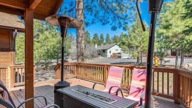 Eine Holzterrasse mit Tisch und Stühlen, mit Blick auf eine Wohngegend mit Bäumen und einem Haus.
