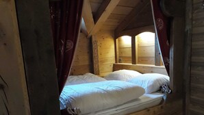 Ein Holzhäuschen-Zimmer mit Bett, Vorhängen und Holzboden.