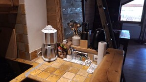 Eine Küchenarbeitsplatte mit Kaffeemaschine, einer Gewürzleiste und einem Holztisch.