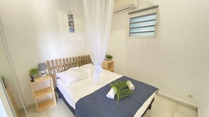 A neatly made bed with a dark blue bedspread, a white canopy, and a small plant on the side. - Villa Ti Ma-El, F2 quiet sea view Sainte-Anne   (sainte anne)