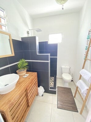 Une salle de bain moderne avec un meuble-lavabo en bois, un lavabo blanc et une petite plante en pot.