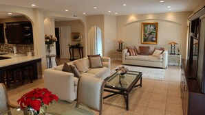 Un salón amplio con sofá, sillones, una mesa de centro y una mesa de comedor.