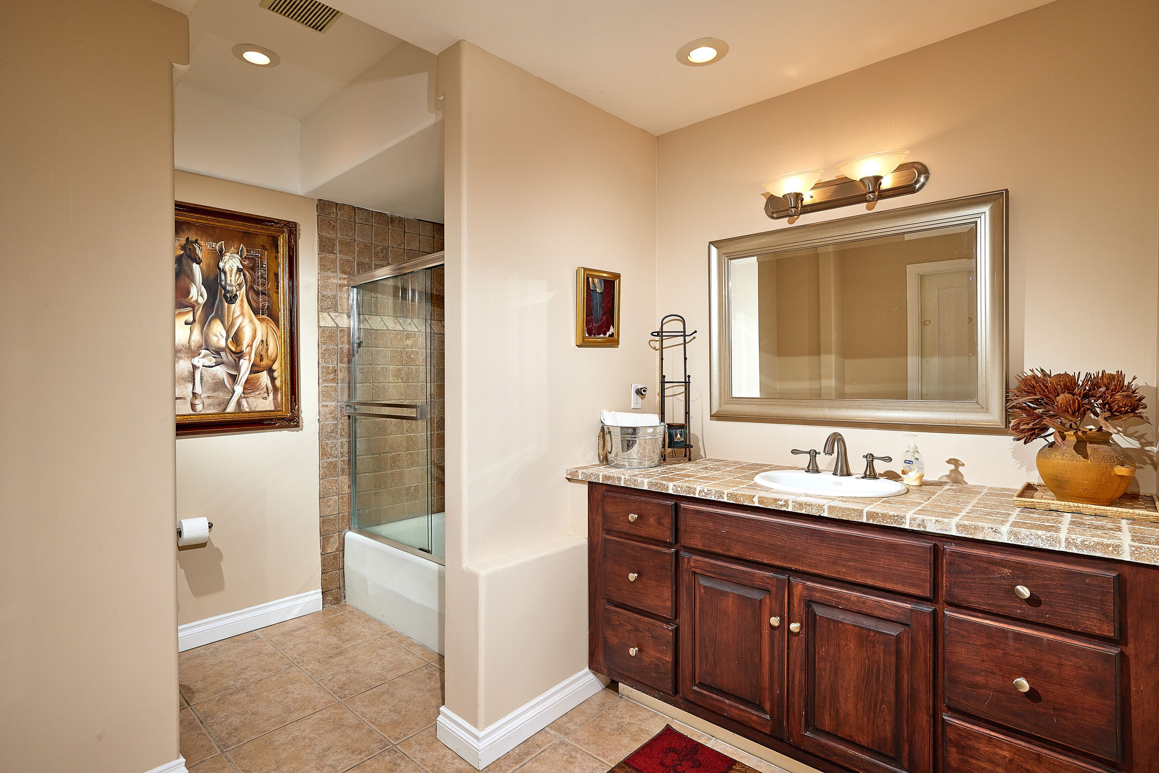 A bathroom with a large mirror, a sink, and a shower.