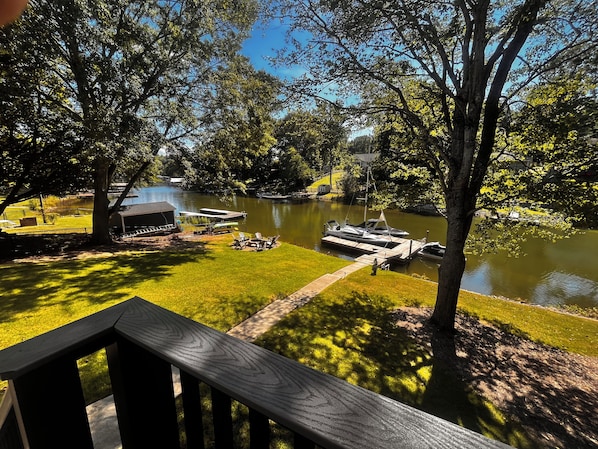 A lakeside deck with a view of a calm lake, docked boats, and surrounding greenery. - Serenity Cove (Denver)
