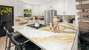 A modern kitchen with marble countertops, stainless steel appliances, and a large island.