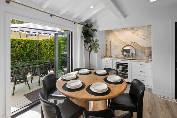 A dining area with a round table set for six, surrounded by black chairs.