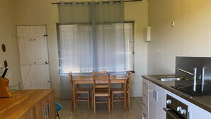 Una cocina moderna con una mesa de comedor, armarios de madera, horno empotrado y una lámpara colgante.