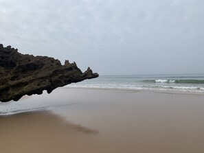 Ein Strand mit einer Felsformation, die sich ins Wasser erstreckt.