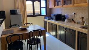Une cuisine équipée d’une table à manger, de chaises, d’un four à micro-ondes, d’une cuisinière et de placards.