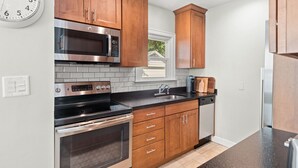 A kitchen with wooden cabinets, stainless steel appliances, and a black countertop.