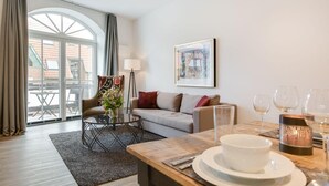 Un salon moderne avec un canapé, un fauteuil, une table basse et une table à manger dressée pour le repas.