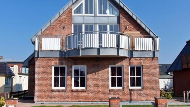 A two-story house with a balcony on the second floor.