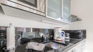 A modern kitchen with stainless steel appliances, a coffee maker, and a sink.