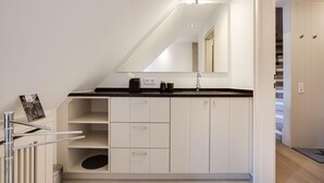 Et moderne badeværelse med skråvæg, stort spejl og sort bordplade.