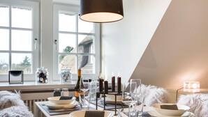 En spiseplads med et bord dækket til fire personer, vinflaske, glas og stearinlys.