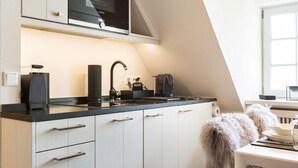 Et moderne køkken med en sort bordplade, hvide skabe, indbygget mikroovn og elkedel.