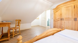 A bedroom with a wooden bed, a wooden chair, a desk, and a wardrobe.